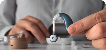 Hands holding a cochlear implant sound processor
