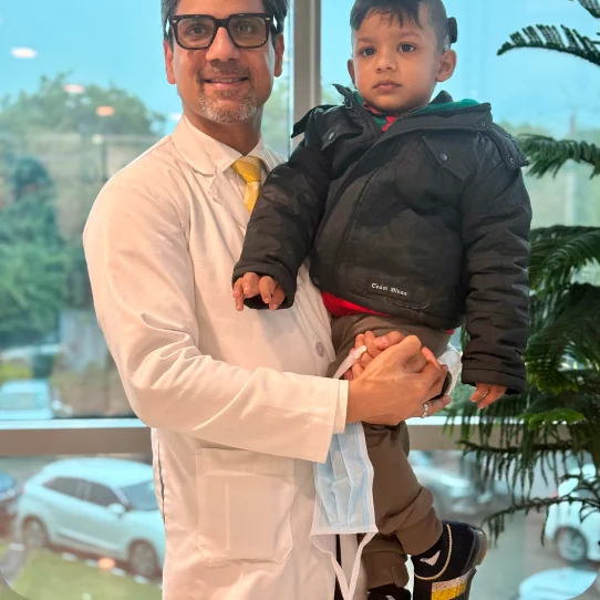 Dr. Sumit Mrig holding a young patient beside the clinic window